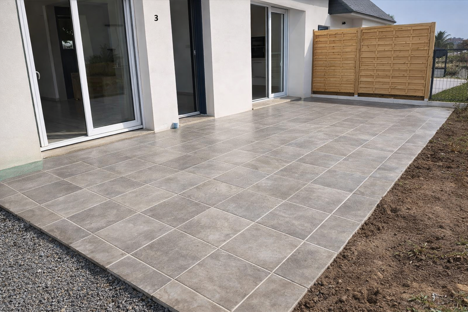 Terrasse carrelée réalisée sur dalle béton devant une maison